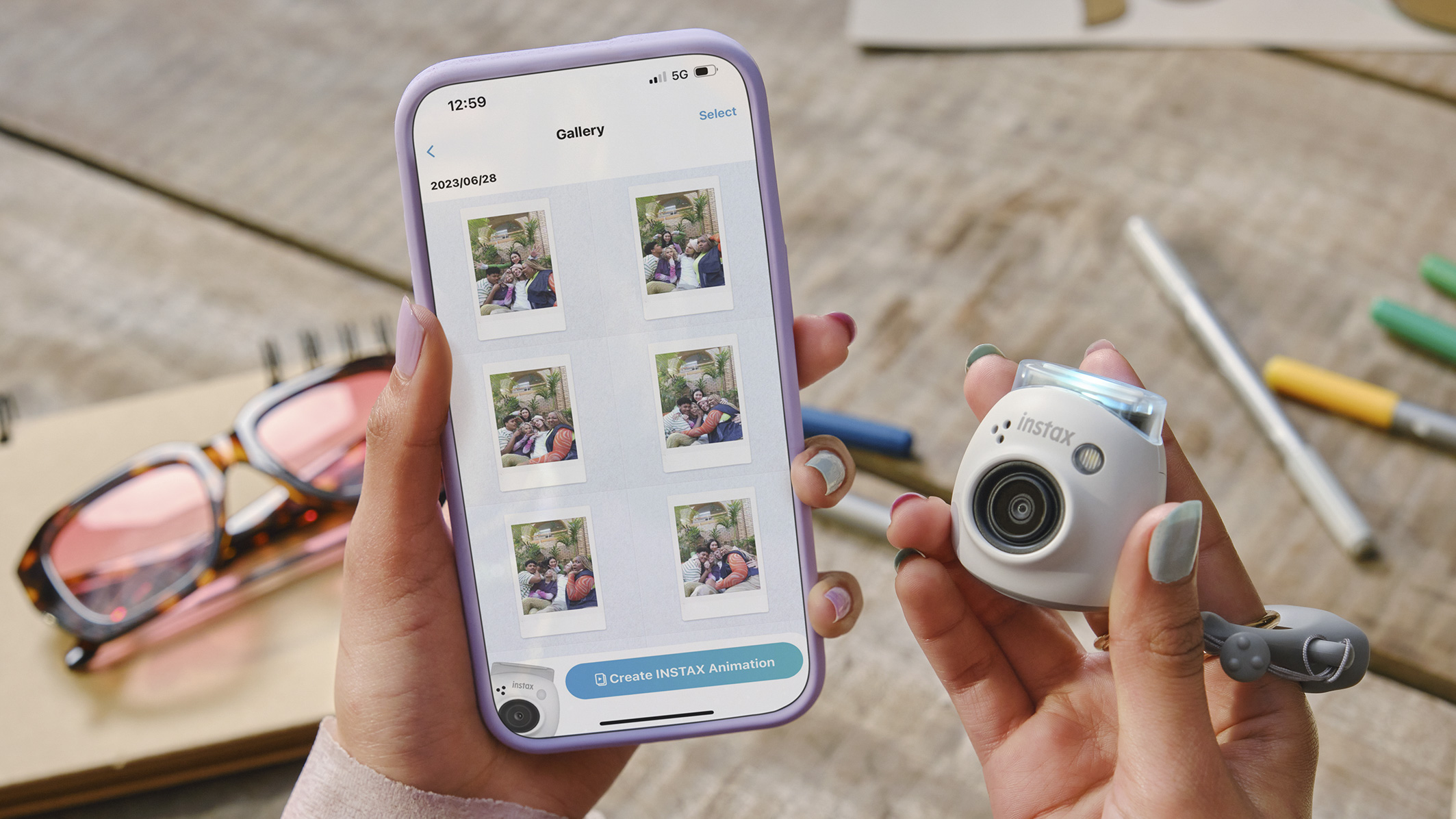 Fujifilm Instax Pal in the hand alongside a smartphone with the Instax Pal app on the phone's display