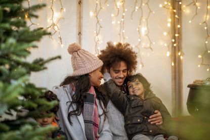 Family sat between a Christmas tree and Christmas lights