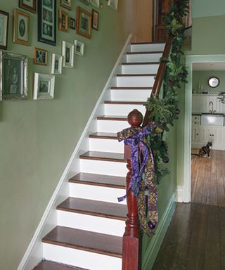 A staircase railing idea decorated with plants and purple ribbon decor
