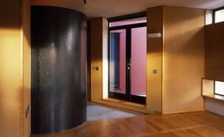 The curve of a black steel shower room within a bedroom, with a private balcony