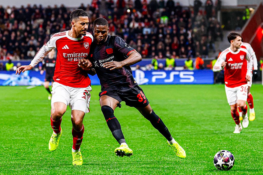 Christian Kofane of Bayer Leverkusen battles for possession with William Saliba in the Champions League