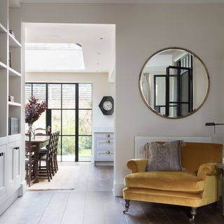 grey living room with mustard velbvet chair and circular mirror