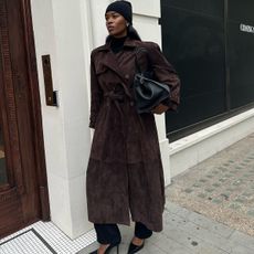 Marilyn Nwawulor-Kazemaks in a black hat, brown suede jacket, and black trousers.