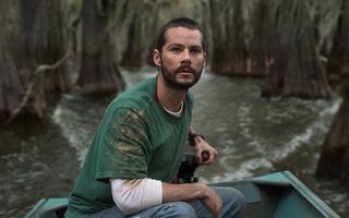 dylan o'brien rides a bow through an eerie lake in the movie caddo lake