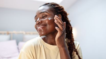 woman applying the best night cream for oily skin to her face 