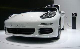 White Porsche S e-hybrid car on a turntable display plugged into a charger