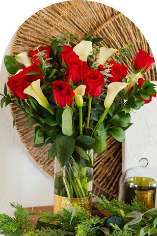 A bouquet of white lilies and red roses in a clear vase