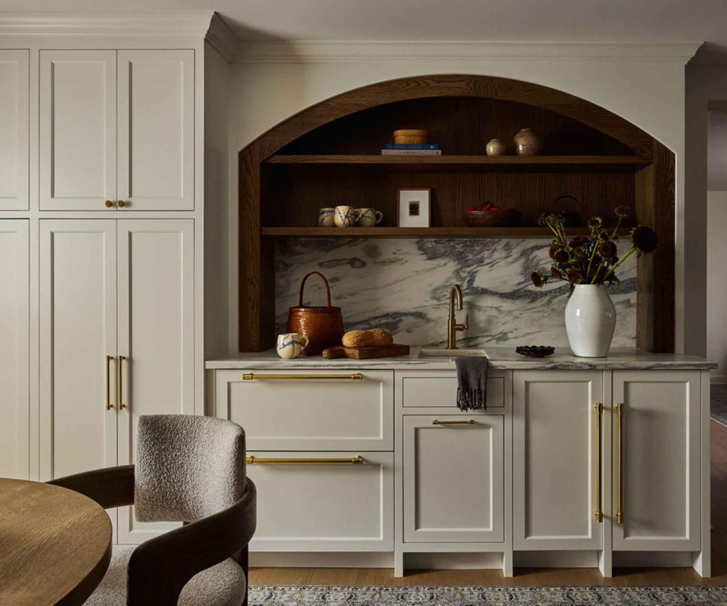 A warm white kitchen with arched shelving designed to look like a hutch