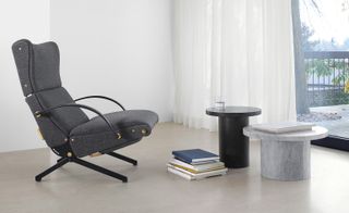 A gray armchair is to the left. Two side tables in gray and black marble are set in front of it.
