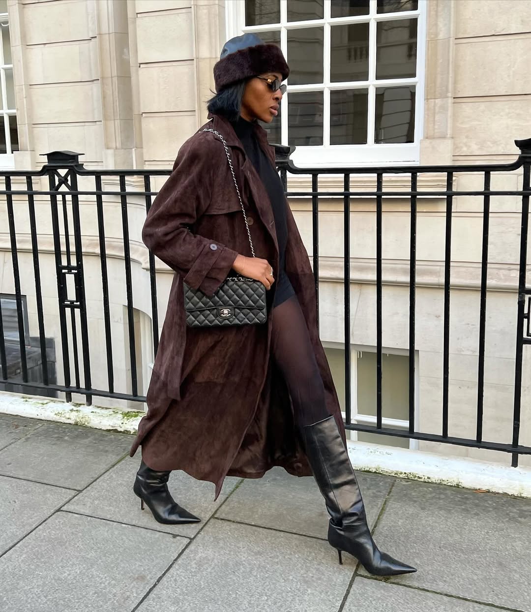 @georgia_3.0 wears a brown suede trench with a black blouse, shorts, tights, knee-high boots, a brown hat and a Chanel bag