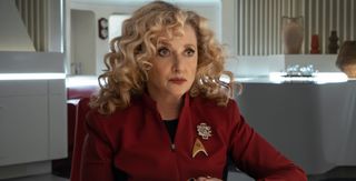a woman with curly hair in a red starfleet uniform