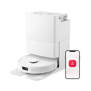 A white robot vacuum with a rectangular base and a mobile phone with a red button next to it