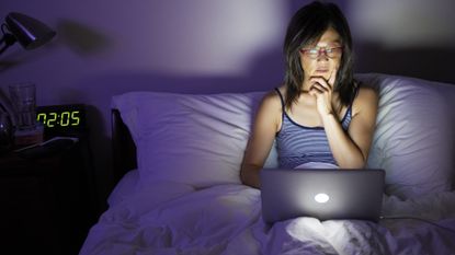 Woman working from her bed on a laptop