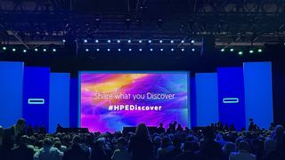 A screen at HPE Discover Barcelona 2024 reading "Share what you Discover" and a hashtag