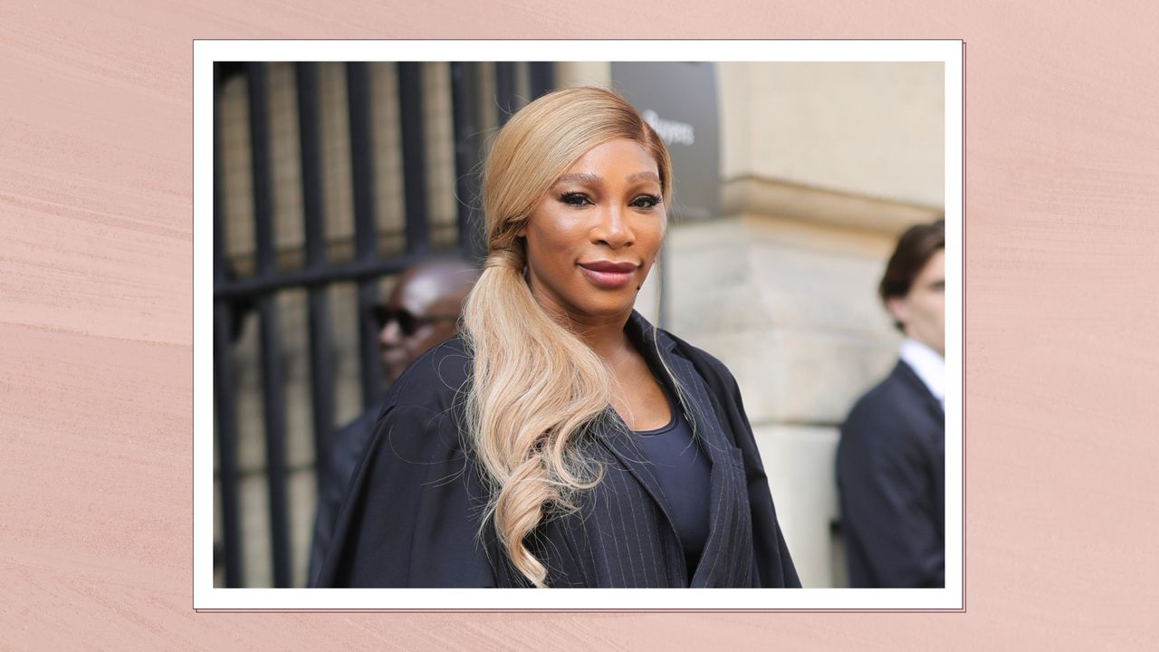 Serena Williams smiling, wearing a tailored black pinstripe dress with a curled side ponytail