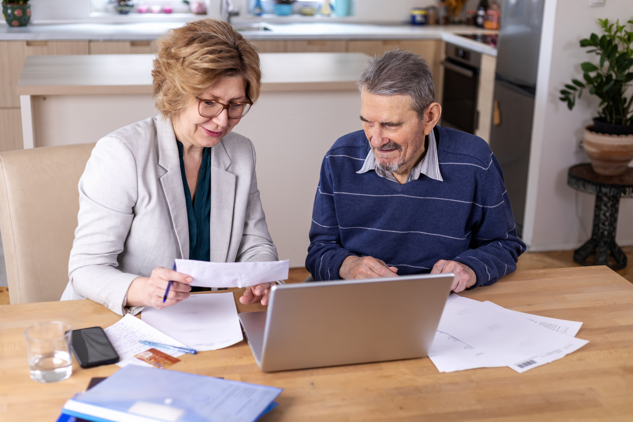 Mature woman helping senior man, 91 years old, with paperwork. He signing documents