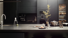 all black seamless kitchen with a wine fridge, double oven and all chrome accessories
