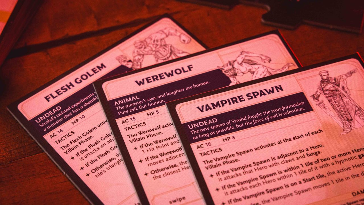 Castle Ravenloft board game components laid out on a dark table, with an ominous red glow on them