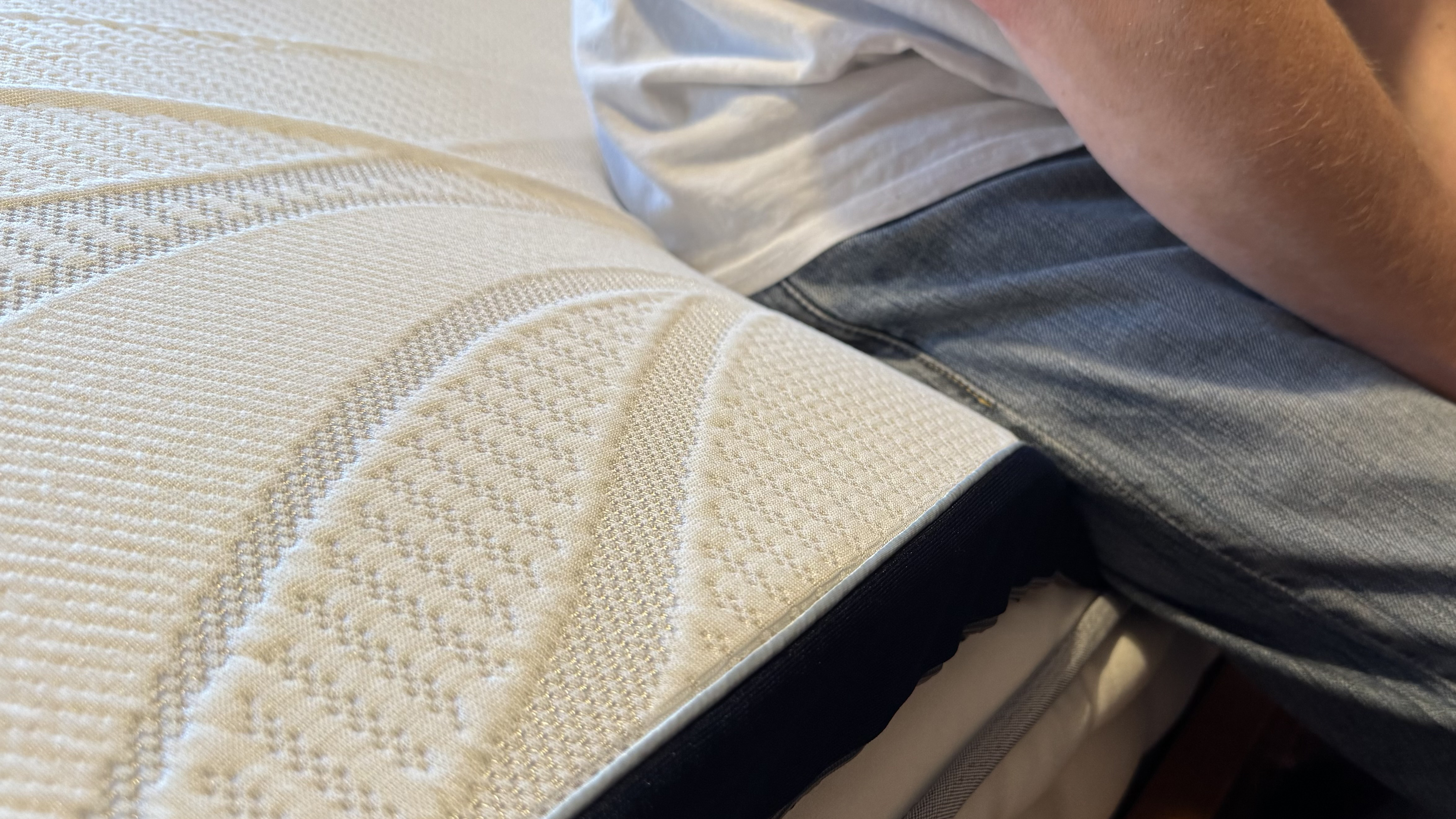 A person sitting on the Nectar mattress topper.