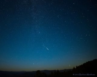 A Perseid meteor flashes through a sky tinged with smoke from forest fires in this image captured by photographer Barbara Matthews from Nevada County, California, during the peak of the 2016 Perseid meteor shower on Aug. 11-12.