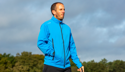 A golfer wears the Ping Taran 3L Rainwear Jacket in light blue