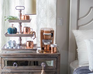 DIY coffee bar beside bed, featuring cozy copper accents