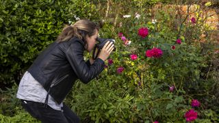 A woman in a leather jacket photographing roses with the Polaroid I-2