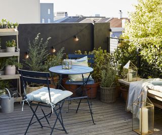 A range of outdoor products from John Lewis including a blue bistro table set and festoon lights and large pillar candles in clear glass lanterns