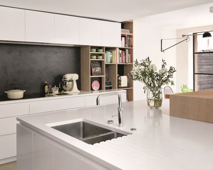 Kitchen with white walls, kitchen island and fitted units, dark grey splash back and built in wooden shelves
