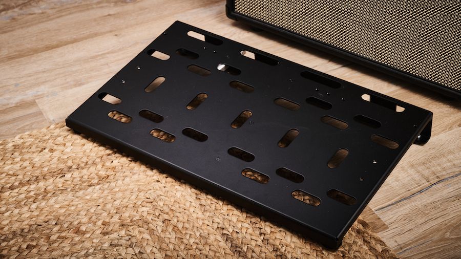 A Voodoo Labs Dingbat Medium pedalboard on a wooden floor with a guitar amp