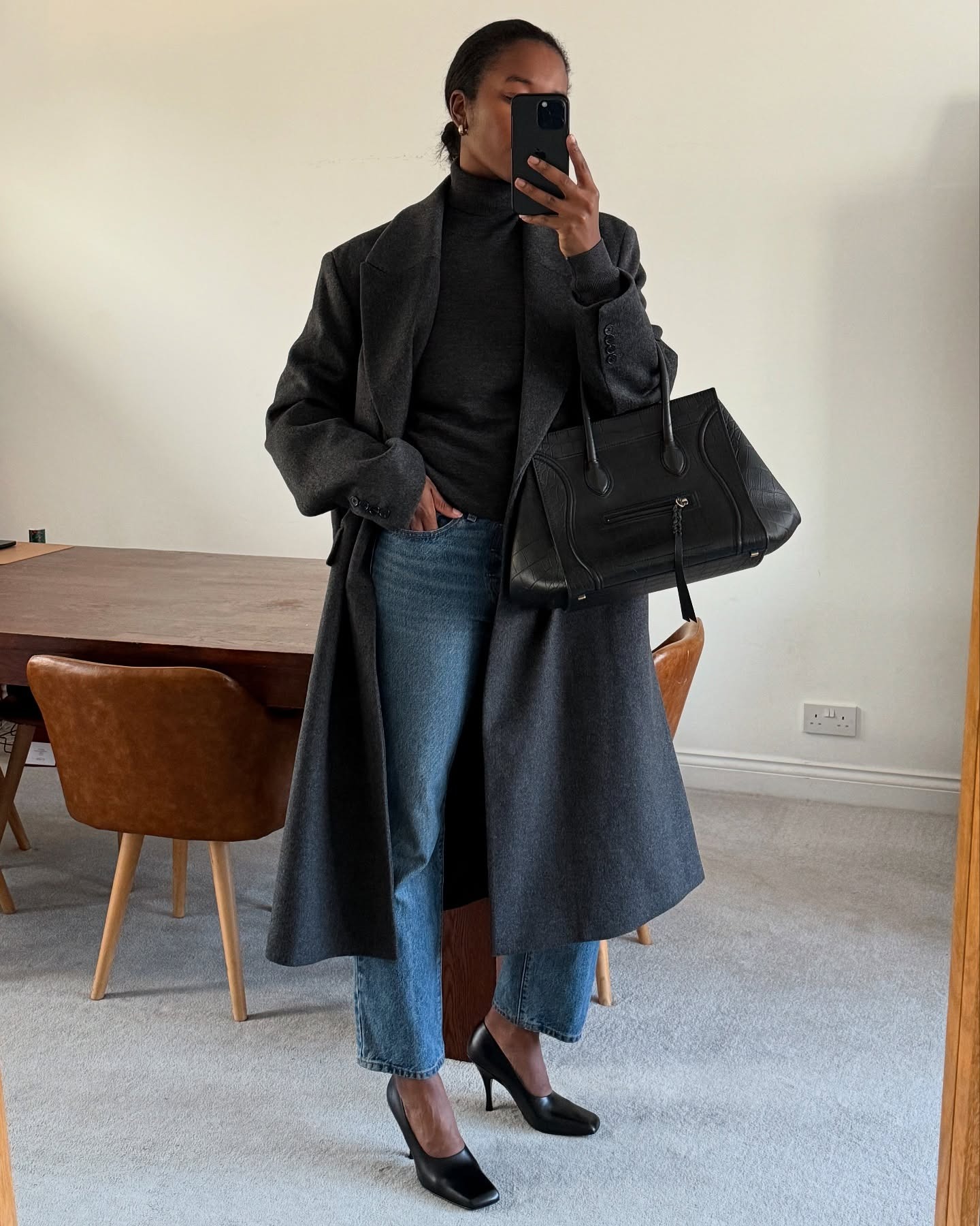 Woman in a gray coat, jeans, and high-vamp pumps