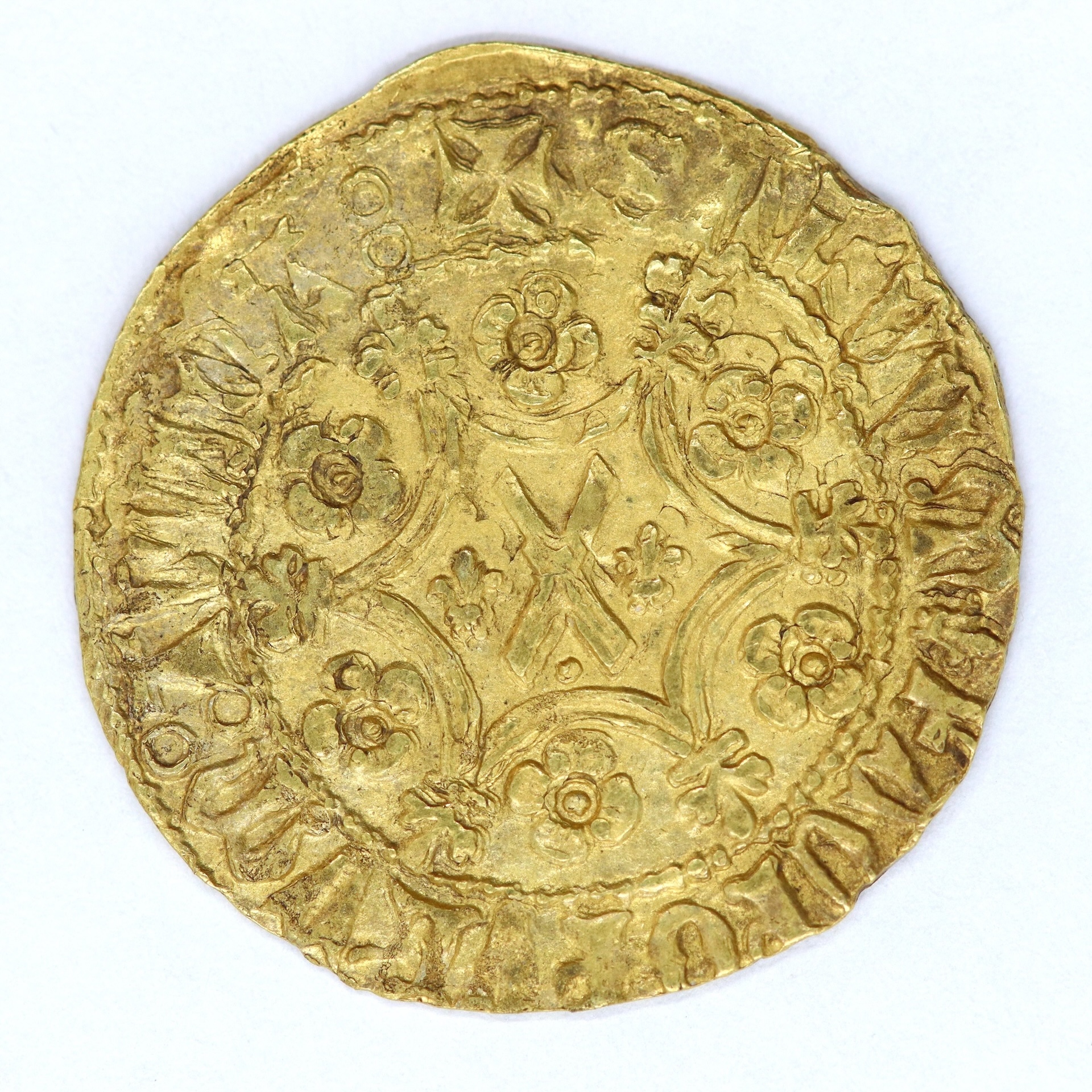 A closeup of a gold coin with decorative motifs