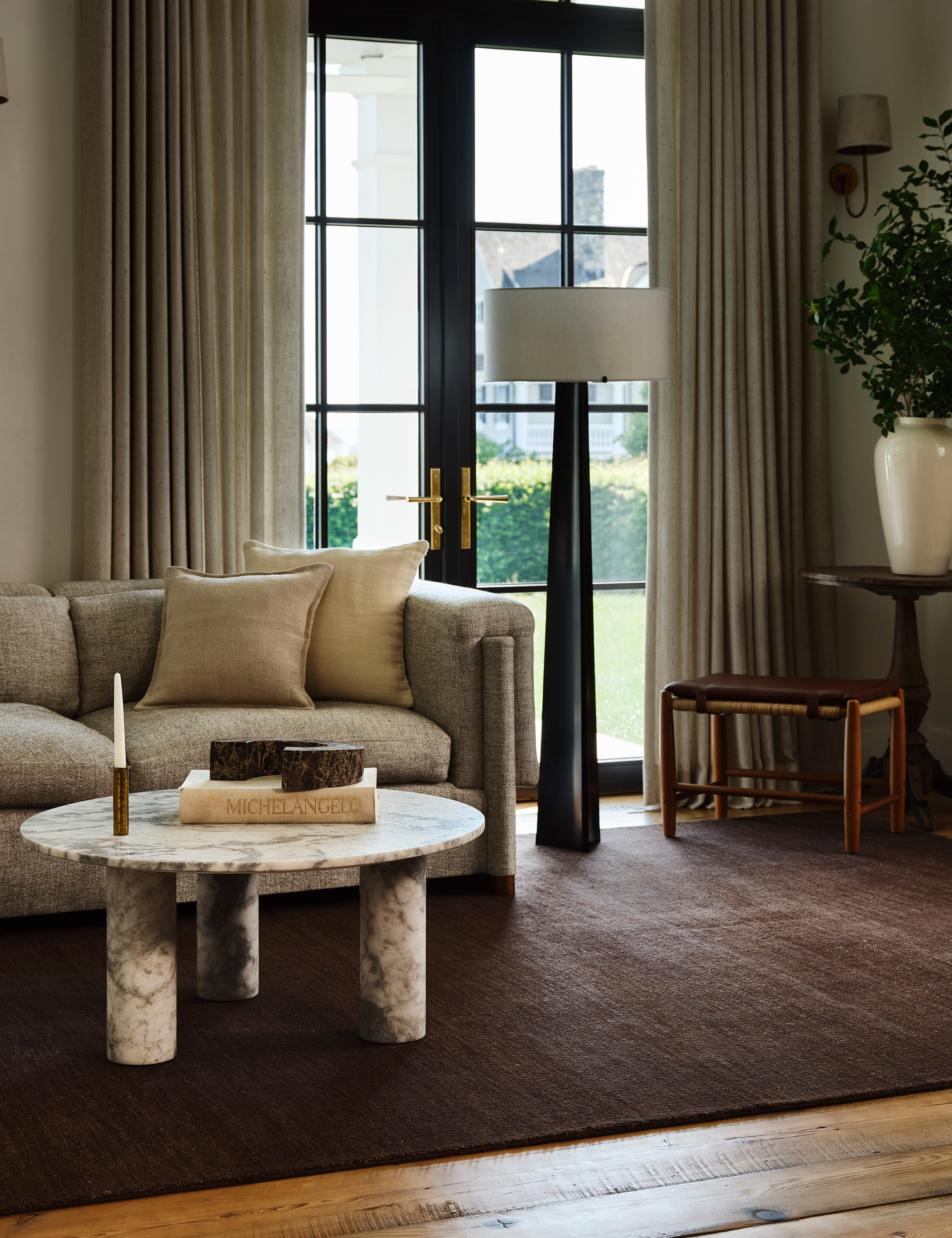 Nate Berkus x Rugs USA purple-brown area rug pictured in a wood-floored living room that features a circular marble coffee table, oversized floor lamp, and neutral furniture