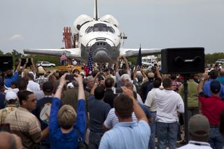 Space shuttle Atlantis is slowly towed from the Shuttle Landing Facility to an orbiter processing facility at NASA's Kennedy Space Center in Florida for the last time on July 21, 2011. A crowd of NASA workers is on hand for an employee appreciation event.