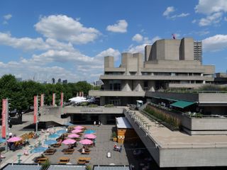 The National Theatre in the sun with parasols and seating outside