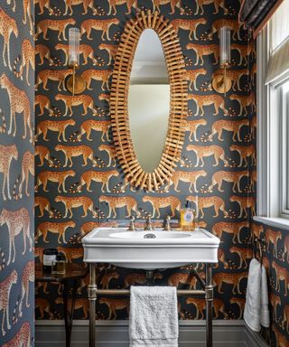 A cloakroom with leopard print wallpaper and a traditional white sink