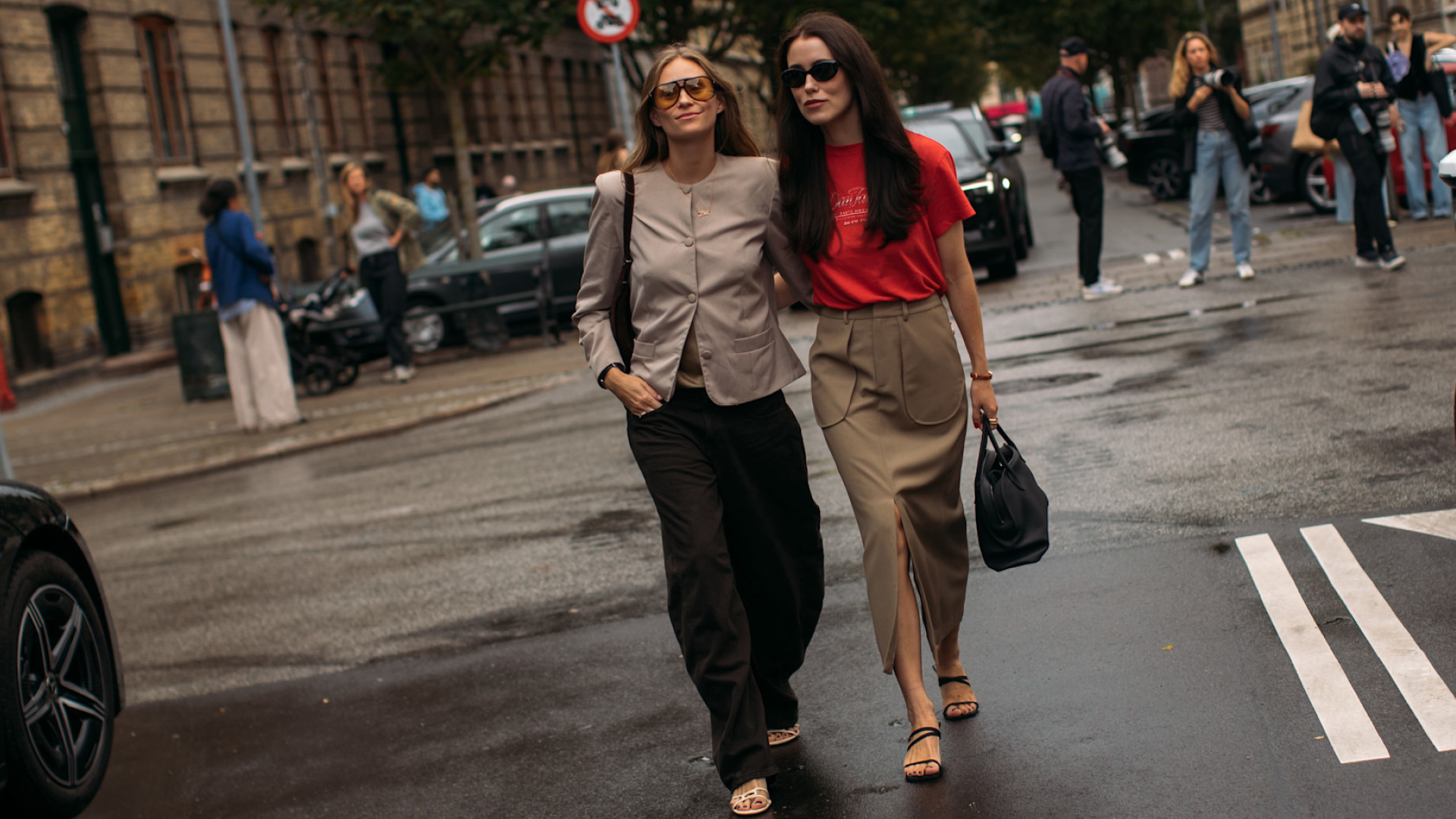 two Copenhagen fashion week attendees crossing the straight with their arms over each other 