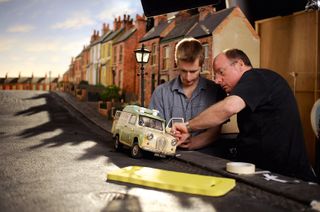Two workers building a model van on a model road