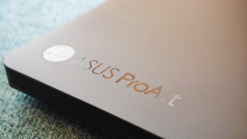 A black ASUS ProArt P16 laptop on a green sofa