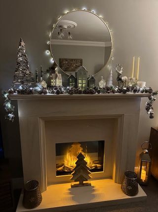 a lit fireplace decorated for Christmas with lights and miniature lit houses