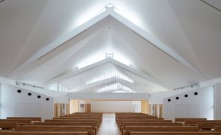 Modern white pointed church with dark wooden benches