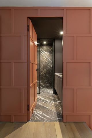 Black marble bathroom behind orange panelled door