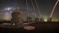 The Milky Way shines over the Very Large Telescope in Chile, as lasers arc skyward from the four background telescopes.