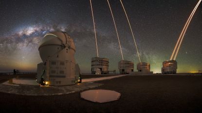 The Milky Way shines over the Very Large Telescope in Chile, as lasers arc skyward from the four background telescopes.