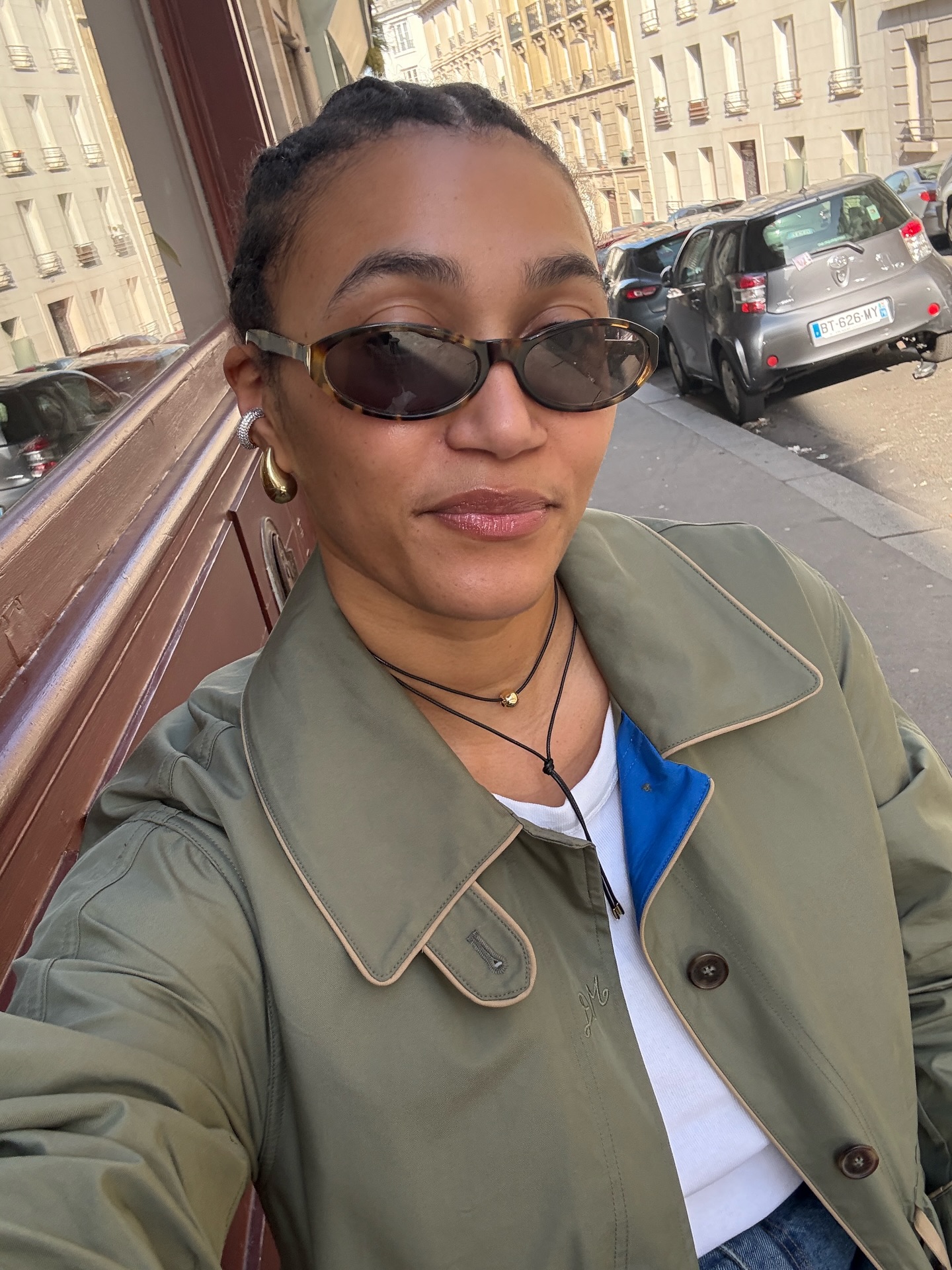 L&eacute;na wearing a khaki jacket, white top with statement gold earrings.