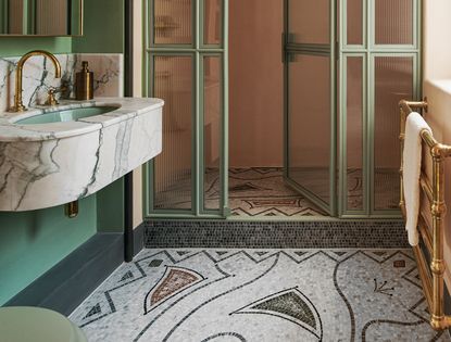 green bathroom with mosaic floor and brass taps