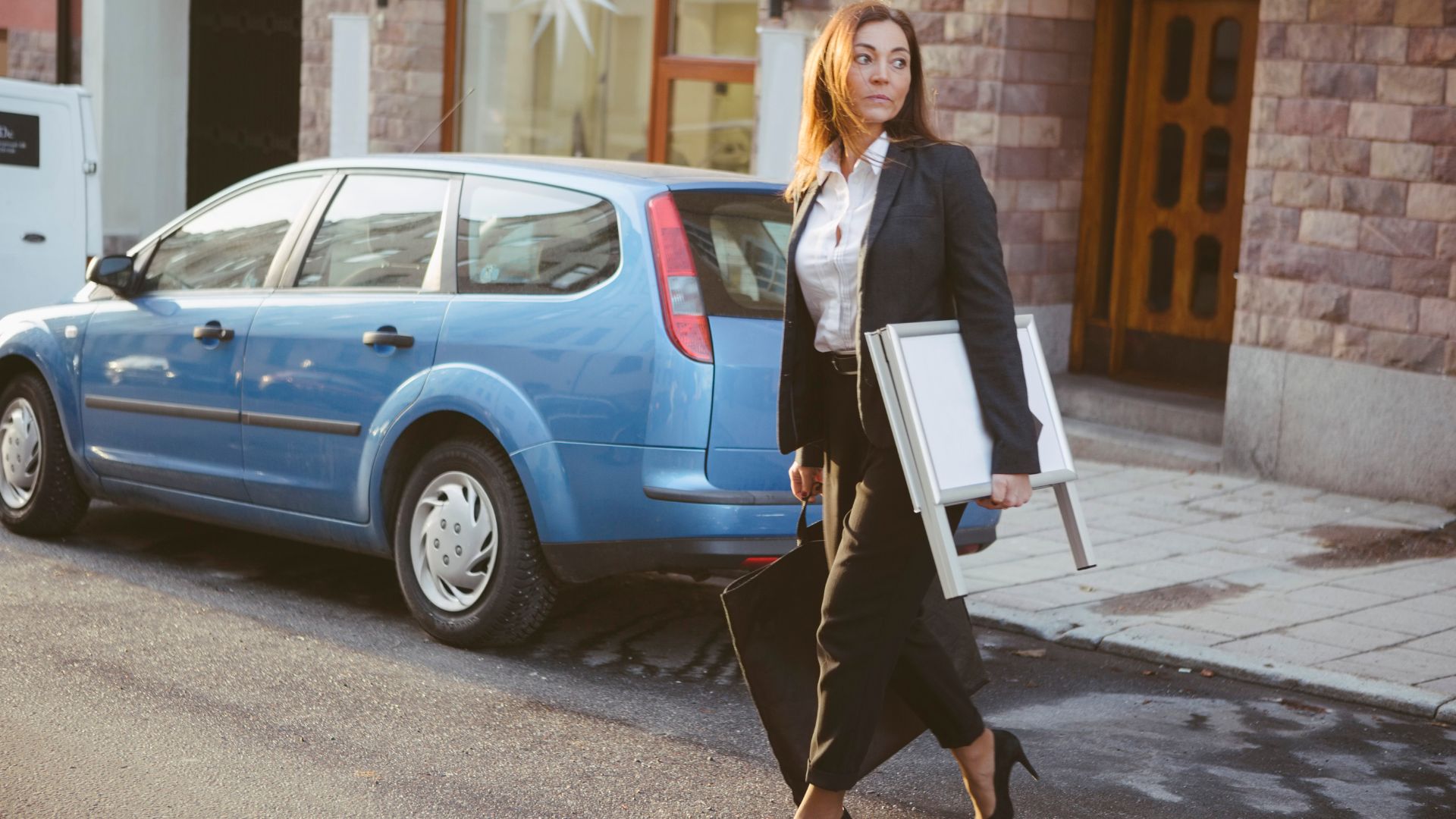 Woman walking across the road from car