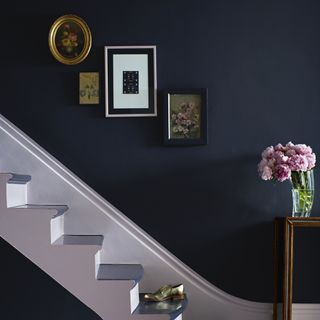 stair case with indigo blue wall and picture frames