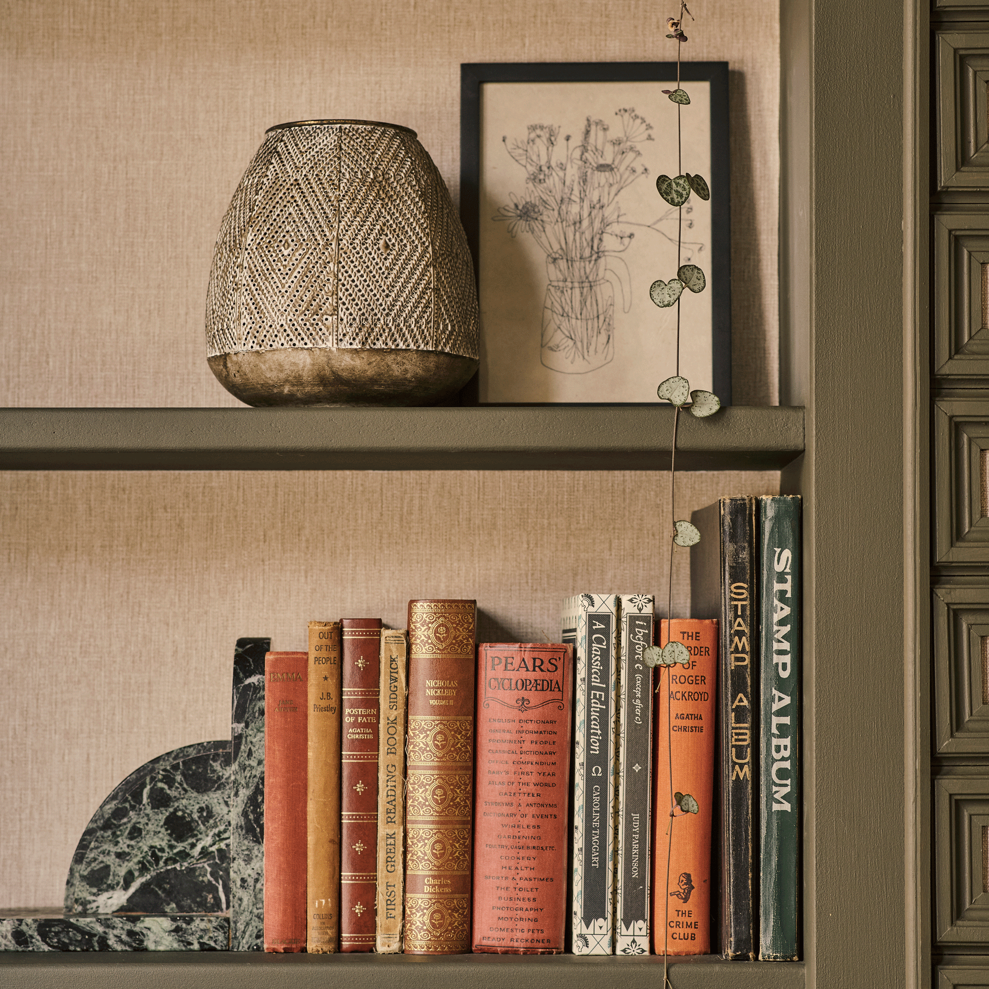 a living room with a close up of a shelf with a collection of vintage books and a green marble bookend