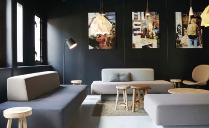 Seating area featuring simplistic furniture, pale flooring and dark walls with photographic artwork